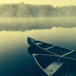 Two canoes wait ready by the shore of an early morning pond.